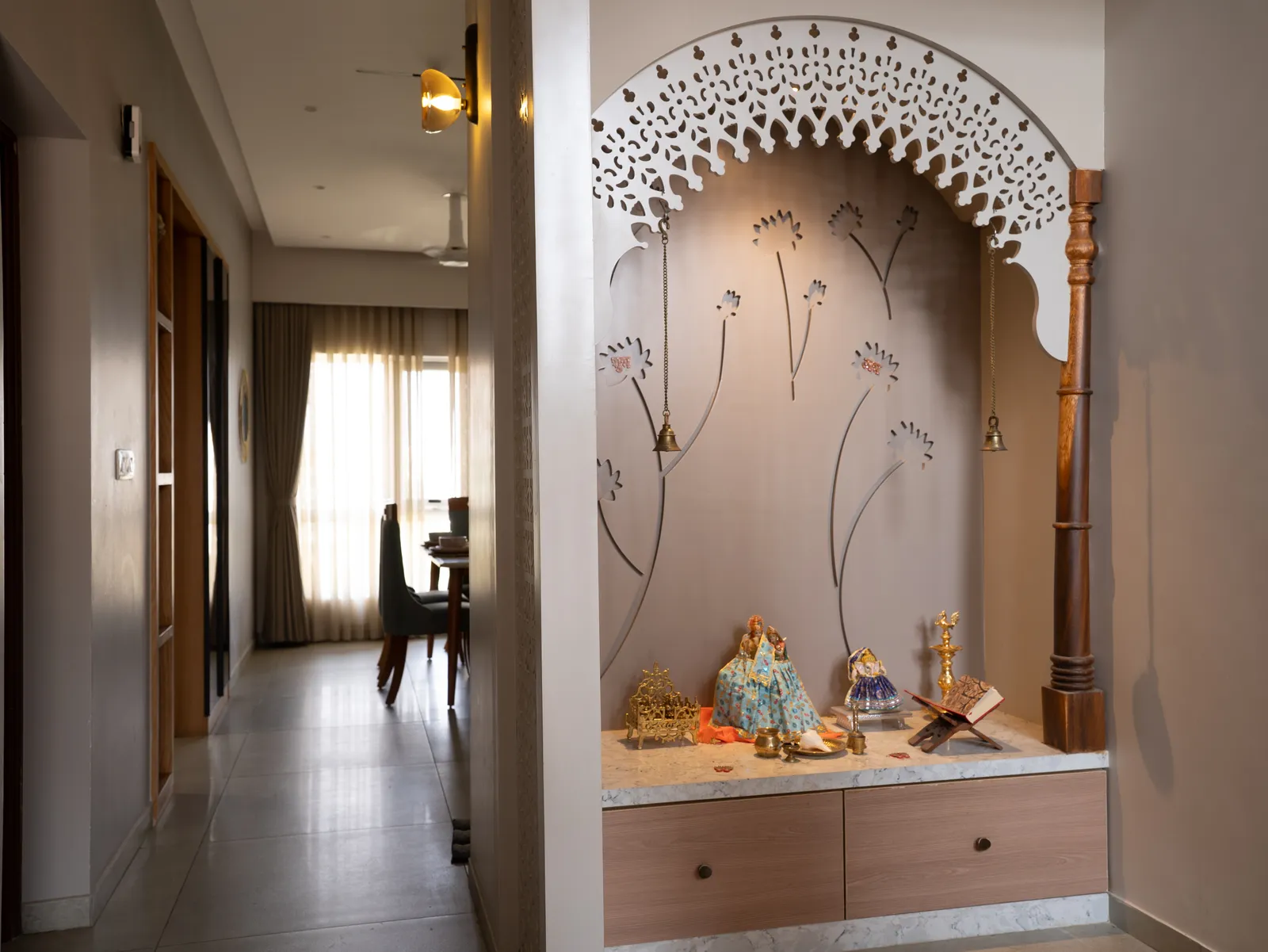 Pooja niche with carved arch and storage drawers — Amlan's Residence